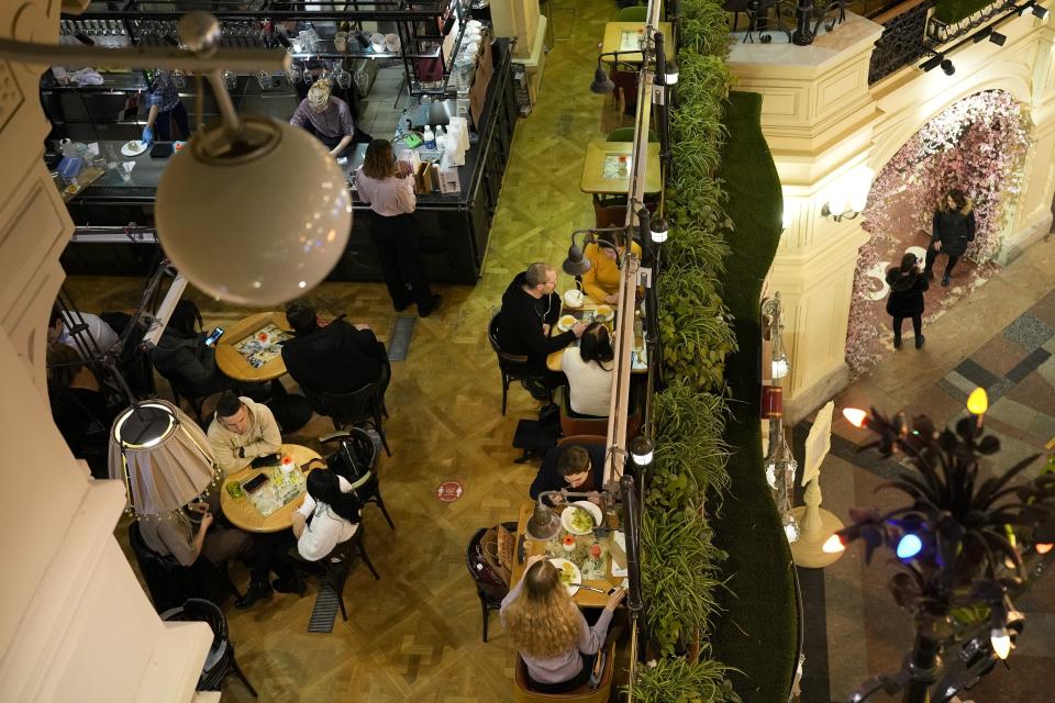 Visitors sit in a cafe inside the GUM department store in Moscow, Russia, late Monday, Feb. 14, 2022. While the U.S. warns that Russia could invade Ukraine any day, the drumbeat of war is all but unheard in Moscow, where political experts and ordinary people alike don't expect President Vladimir Putin to launch an attack on the ex-Soviet neighbor. (AP Photo/Alexander Zemlianichenko)