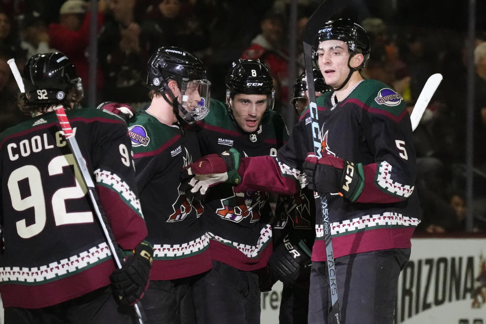 Arizona Coyotes center Nick Schmaltz (8) celebrates after his goal against the Washington Capitals with center Logan Cooley (92), defensemen Juuso Valimaki, second from left, and Nick Schmaltz (8) during the first period of an NHL hockey game Monday, Dec. 4, 2023, in Tempe, Ariz. (AP Photo/Ross D. Franklin)