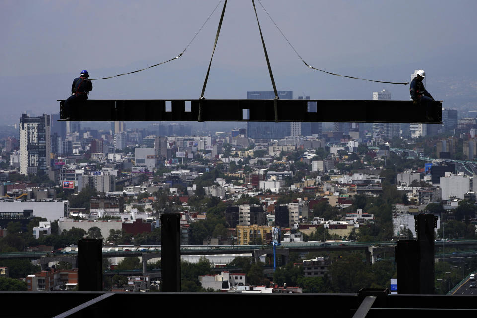 FILE - Construction workers ride on a beam hanging from a crane at the construction site of a residential high rise building in Mexico City, June 17, 2022. Hobbled by high interest rates, punishing inflation and Russia's war against Ukraine, the world economy is expected to eke out only modest growth this year and to expand even more tepidly in 2023. That was the sobering forecast issued Tuesday Nov. 22, 2023 by the Organization for Economic Cooperation and Development. In the OECD's estimation, the world economy will grow just 3.1% this year, down sharply from a robust 5.9% in 2021. (AP Photo/Marco Ugarte, File)