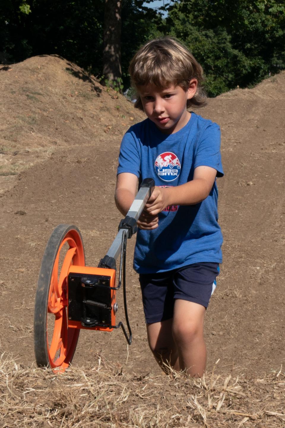 Connor Grist, 5, helps measure distances using a rolling measuring device, as he and other volunteers work Sept. 2 at Topeka's Heartland BMX, 4801 S.W. Shunga Drive in Crestview Park.