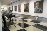 A journalist films the black ribbon and a bouquet of flowers adorning the portrait of former United Nations Secretary-General Kofi Annan at U.N. headquarters, Saturday, Aug. 18, 2018. Annan, one of the world's most celebrated diplomats and a charismatic symbol of the United Nations who rose through its ranks to become the first black African secretary-general, has died. He was 80. (AP Photo/Mary Altaffer)