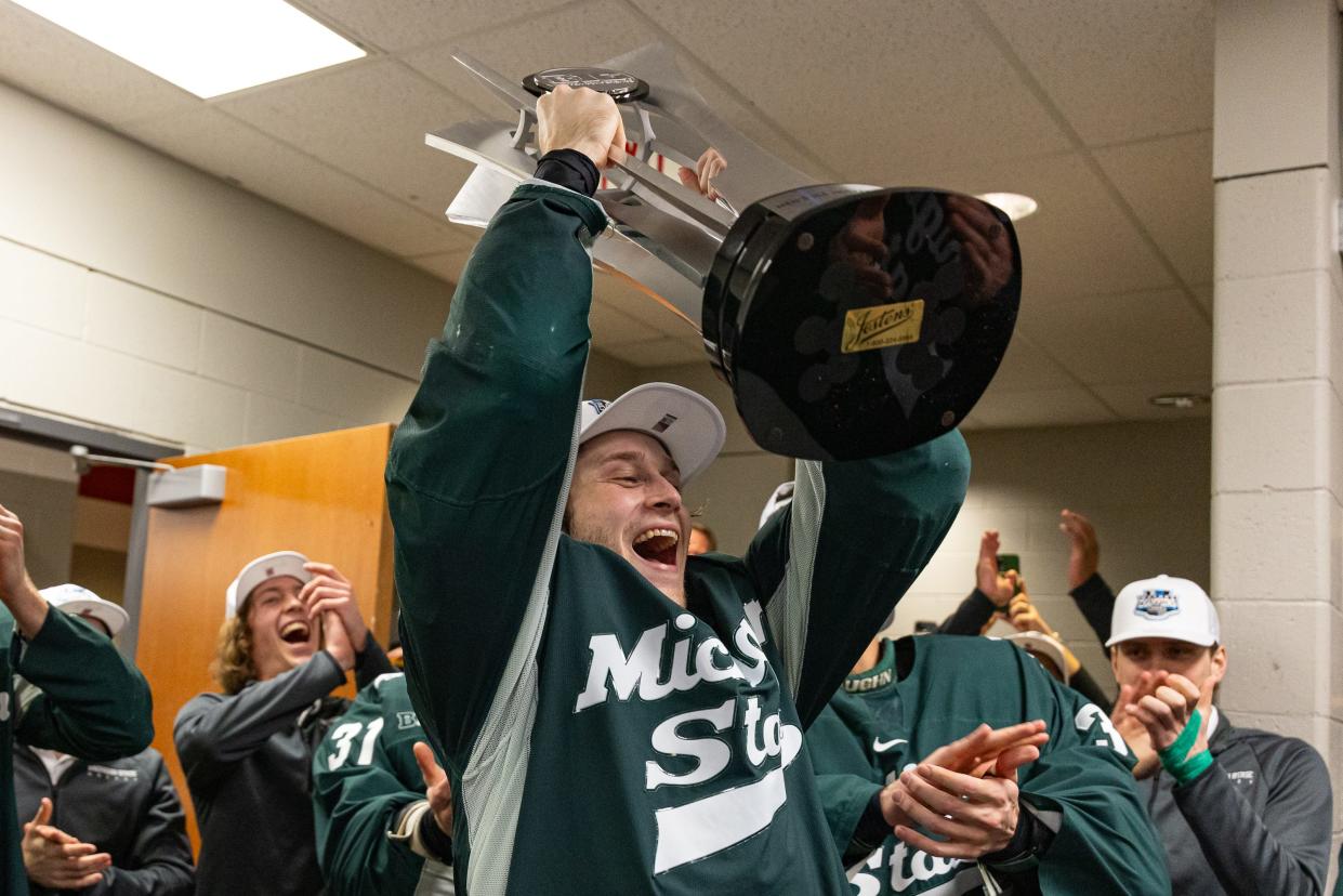 Michigan State forward Reed Lebster hoists the Big Ten regular-season trophy in celebration following MSU's 5-2 win over Wisconsin on March 1, 2024, at the Kohl Center in Madison, Wisconsin.