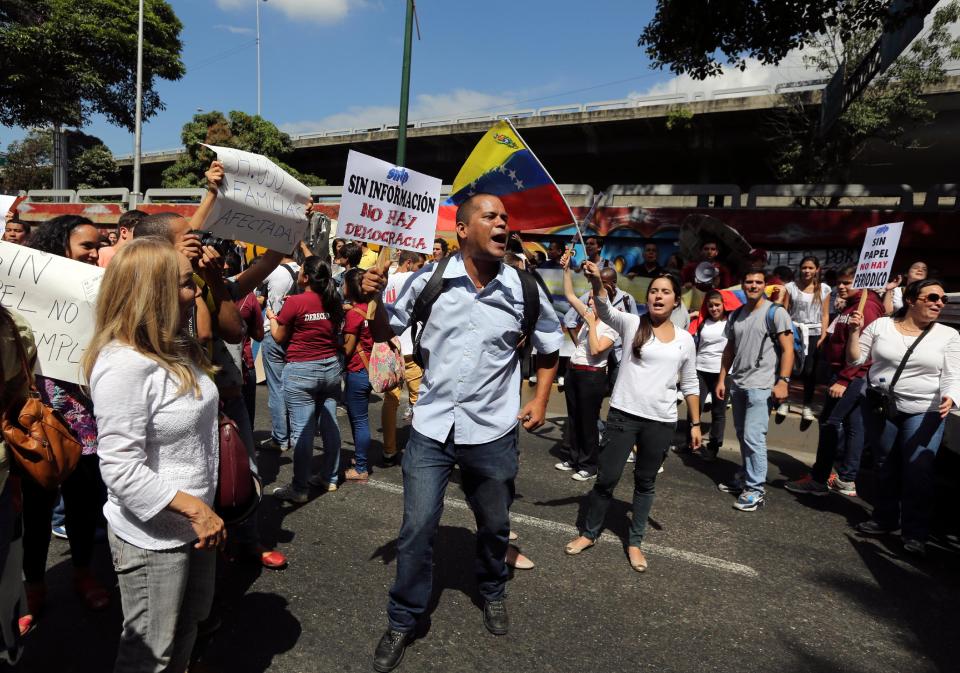 An employee of El Nacional newspaper holds up a sign that reads in Spanish "Without information, there is no democracy", during a protest outside the Cadivi agency, which controls foreign currency in Caracas, Venezuela, Tuesday, Jan. 28, 2014. While newspapers have been beset for years by currency controls that make it difficult to import supplies, El Nacional is scrambling for newsprint as worsening shortages threaten to take several publications out of circulation in the coming weeks as reserves of newsprint have fallen to an all-time low. (AP Photo/Fernando Llano)