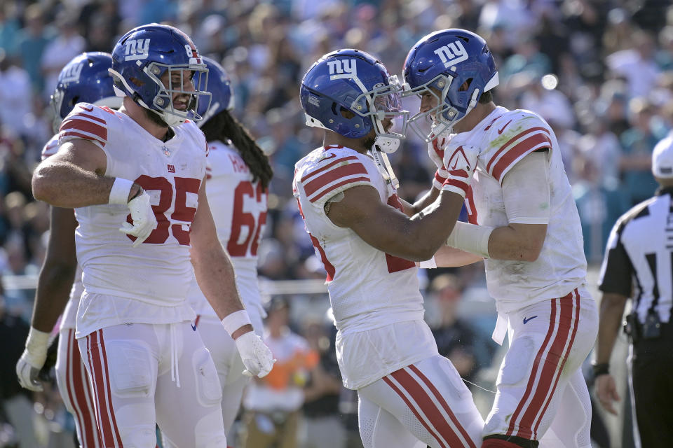 New York Giants quarterback Daniel Jones (8, right) celebrates with running back Saquon Barkley (26) and fullback Chris Myarick (85) after Jones scored on a 1-yard touchdown run against the Jacksonville Jaguars during the second half of an NFL football game Sunday, Oct. 23, 2022, in Jacksonville, Fla. (AP Photo/Phelan M. Ebenhack)