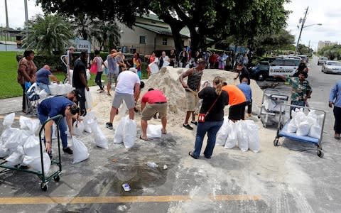 Residents line up at Frost Park in Dania Beach, Fla., and fill up sandbags - Credit: Mike Stocker/South Florida Sun-Sentinel/AP