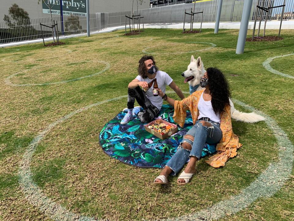 Pictured are two people and a dog sitting in one of the circles in the Chapel St Precinct. 