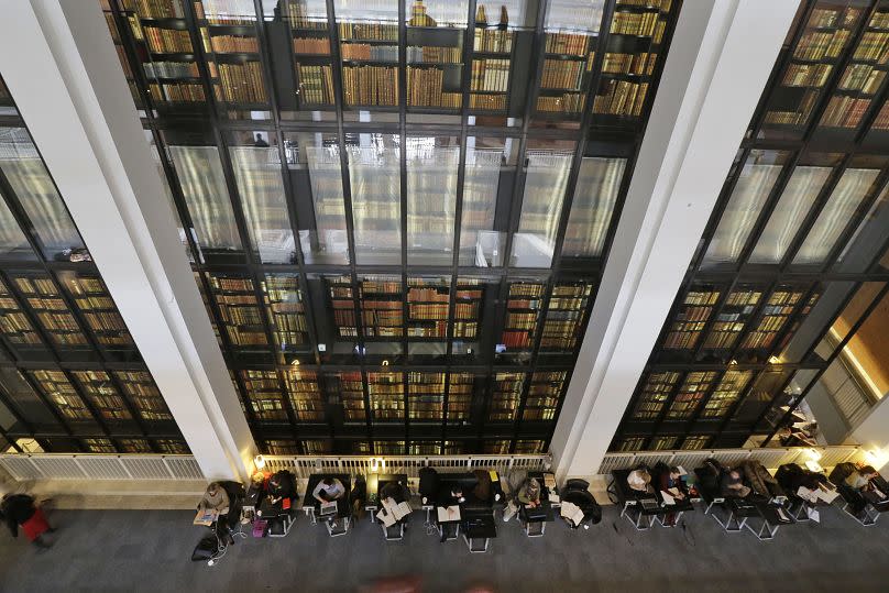 People work behind a backdrop of books at the British Library
