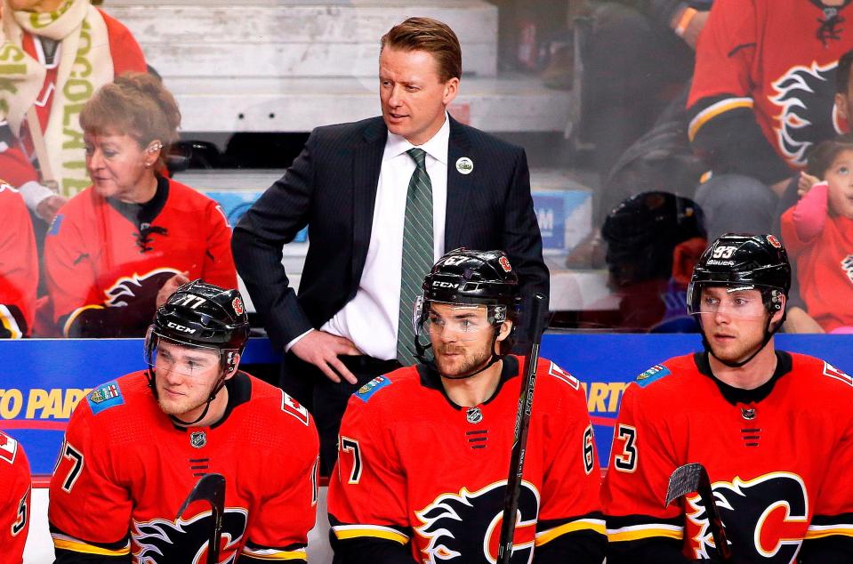 FILE - In this Saturday, April 7, 2018, file photo, Calgary Flames coach Glen Gulutzan, top, watches during the team's NHL hockey game against the Vegas Golden Knights in Calgary, Alberta. The Flames fired Gulutzan on Tuesday, April 17, 2018, after two years with the club. Assistant coaches Dave Cameron and Paul Jerrard were also relieved of their duties. (Larry MacDougal/The Canadian Press via AP, File)