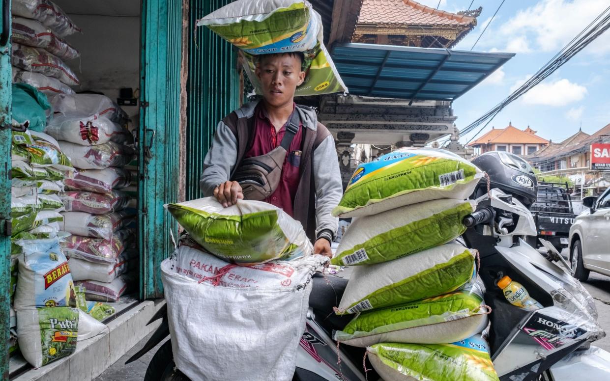 A man loads sacks of rice onto his scooter in Denpasar, Bali province, Indonesia