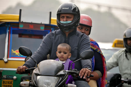 FILE PHOTO: A man wears a mask to protect himself from the pollution as he rides a motorbike in Delhi, India November 7, 2016. REUTERS/Cathal McNaughton