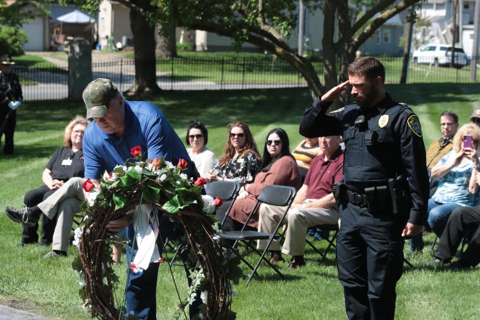 Adrian Police Chief Vince Emrick, right, salutes, Monday as Rick Williams, brother of Adrian Police Officer Bobby Williams, places a rose in a wreath for Bobby Williams during the annual Peace Officers Memorial Day service at Oakwood Cemetery in Adrian.