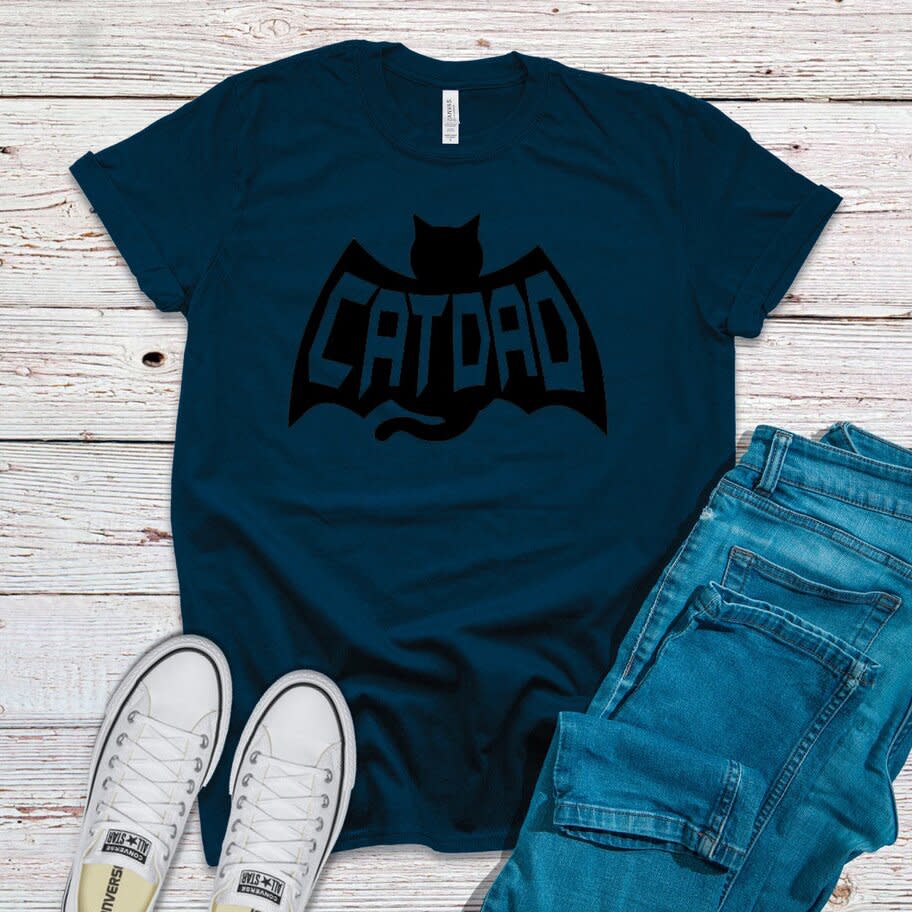 Product photo of a Bat Cat Dad Shirt on a wooden surface with shoes and jeans