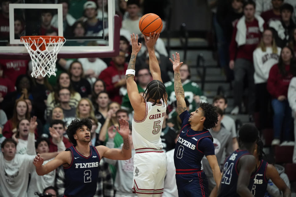 Saint Joseph's Lynn Greer III (5) goes up for a shot against Dayton's Javon Bennett (0) and Nate Santos (2) during the first half of an NCAA college basketball game, Tuesday, Feb. 6, 2024, in Philadelphia. (AP Photo/Matt Slocum)