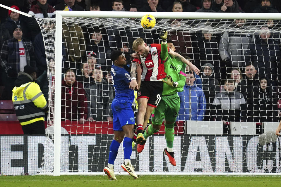 West Ham United goalkeeper Alphonse Areola, right, challenges Sheffield United's Oli McBurnie which results in a penalty kick for Sheffield United, during the English Premier League soccer match between Sheffield United and West Ham United at Bramall Lane, in Sheffield, England, Sunday, Jan. 21, 2024. (Nick Potts/PA via AP)