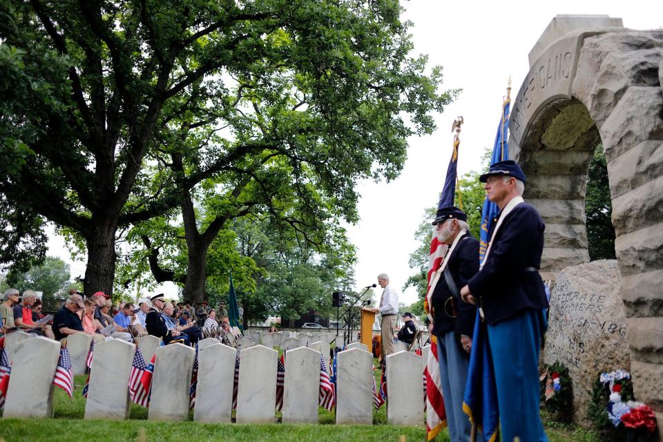 Hilltop Historical Society president Dave Dobos speaks as Robert L. Grove, right back, and Jim Ruley, right front, members of the Gov. William Dennison Camp #1 Sons of Union Veterans of the Civil War, stand in front of the stone arch monument at the Camp Chase Confederate Cemetery on the Hilltop on June 10, 2018.   Camp Chase was a training camp for Ohio volunteer soldiers for the Civil War and also a prisoner-of-war camp for Confederates. The cemetery contains the graves of 2,260 Confederates.