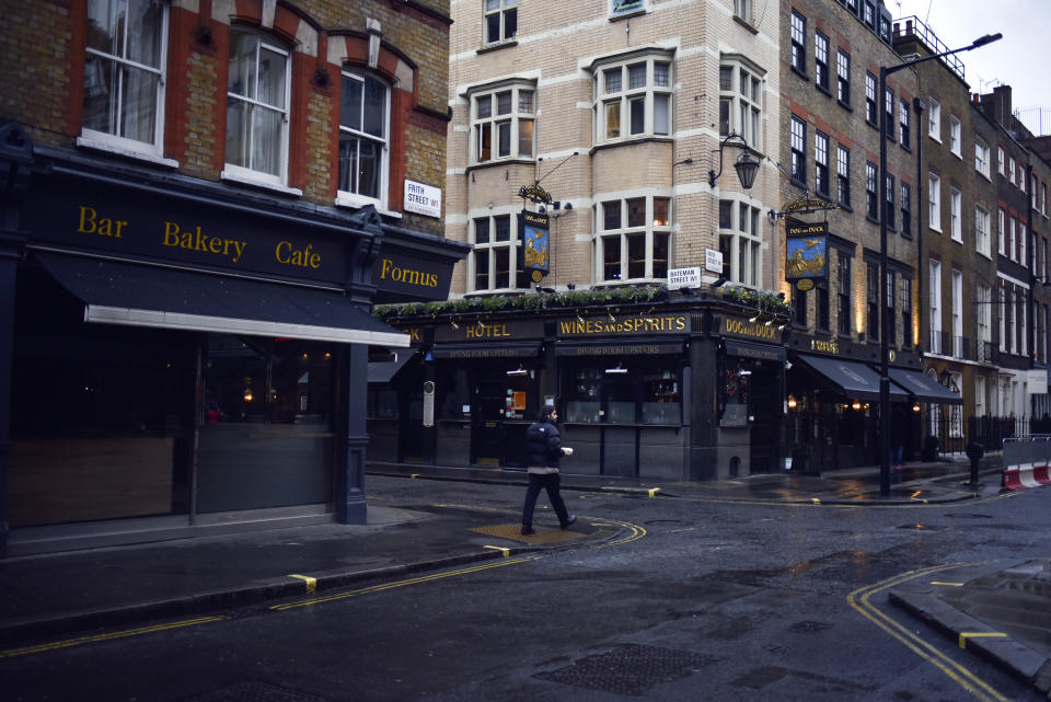 People walk past a closed pub in Soho, in London, Wednesday, Dec. 16, 2020. London and some of its surrounding areas will be placed under Britain's highest level of coronavirus restrictions beginning at 00:01 local time on today as infections rise rapidly in the capital. Under Tier 3 restrictions, the toughest level in England's three-tier system, people can't socialize indoors, and bars, pubs and restaurants must close except for takeout.(AP Photo/Alberto Pezzali)