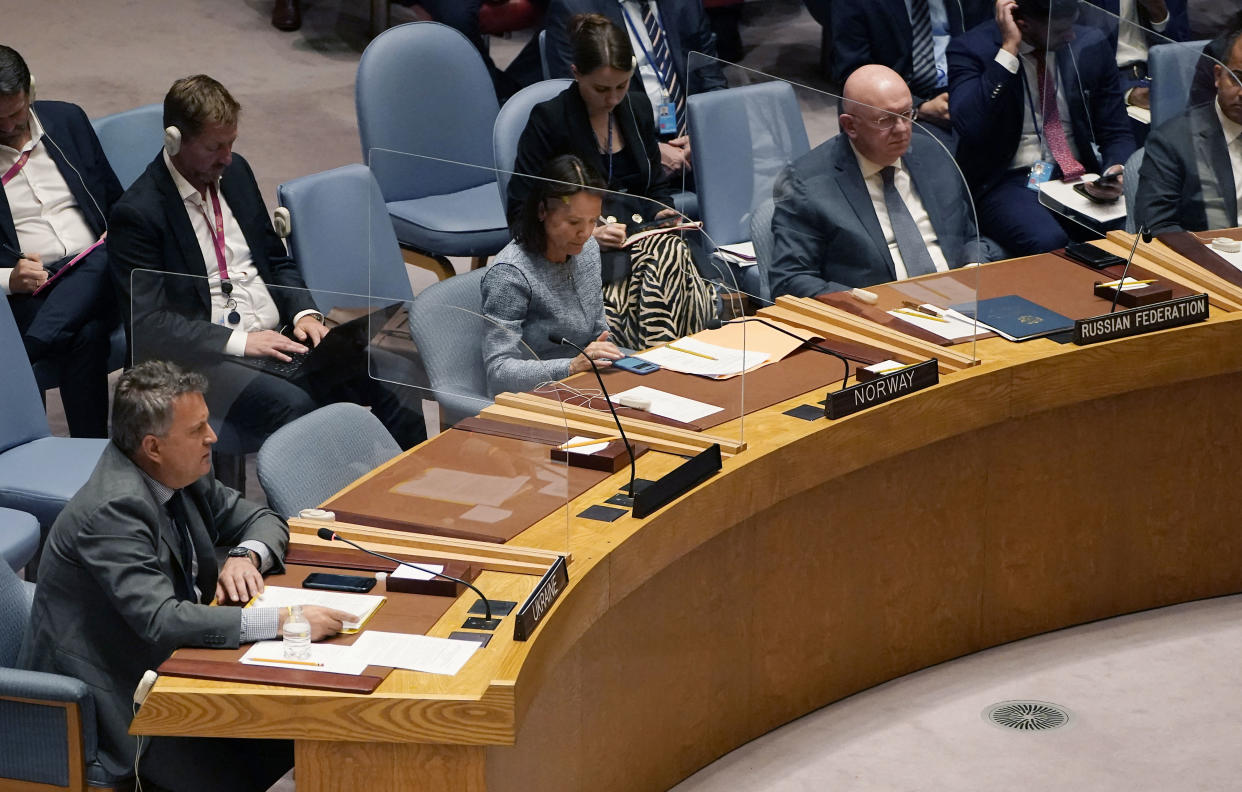 Ukraine representative to the United Nations Sergiy Kyslytsya sits at a curved desk near Russia's U.N. Ambassador Vasily Nebenzya, among others seated between them and in chairs behind them.