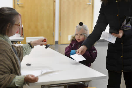 A child watches as voter casts her ballot during presidential election in Helsinki, Finland January 28, 2018. Lehtikuva/Heikki Saukkomaa/via REUTERS