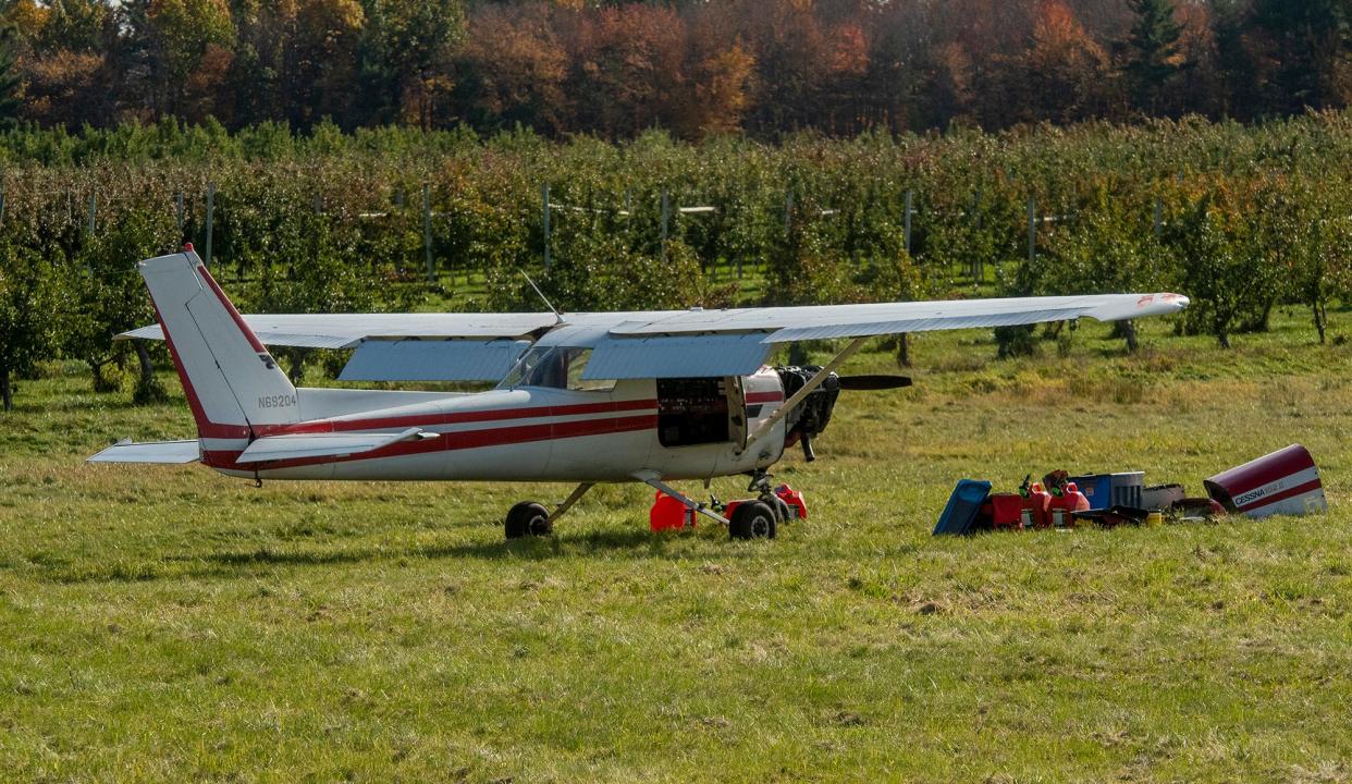 A single-engine airplane sits in a field between Davis Farmland and a neighboring orchard Thursday in Sterling, a day after a pilot landed the Cessna 152 after it reportedly lost power. Crews were getting ready to remove the plane Thursday afternoon. After the fuel is drained from the wing tanks, the wings will be removed and the plane will be towed from the field.