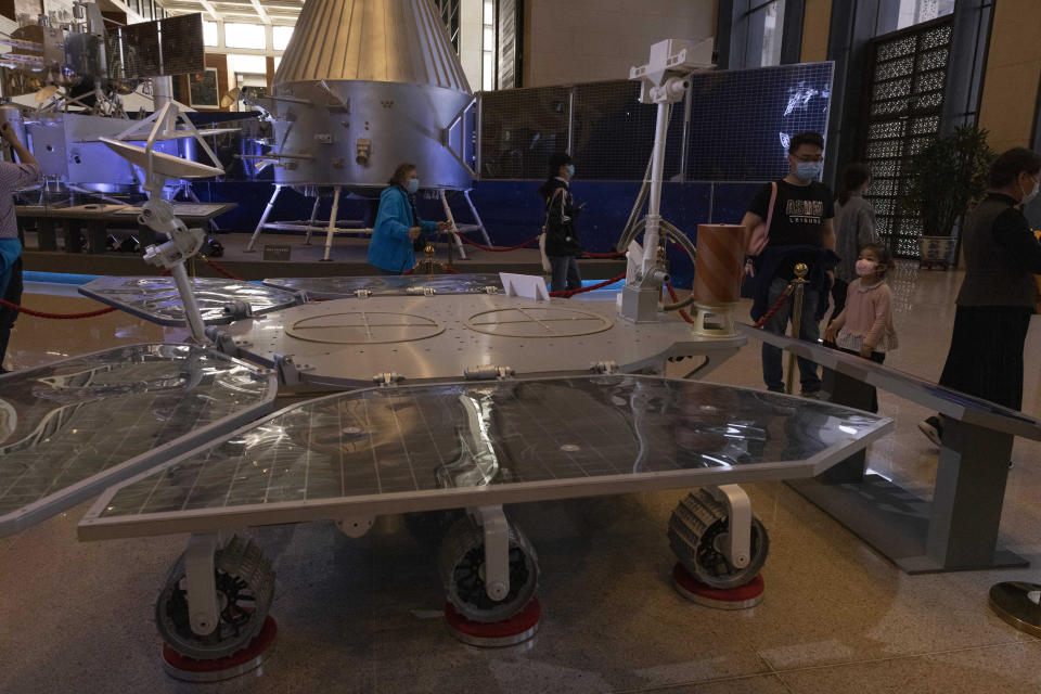 Visitantes a una exhibición del programa espacial de China el jueves 6 de mayo de 2021 observan un modelo de tamaño real de la sonda rodante Shurong, llamada como el dios chino del fuego, en el Museo Nacional, en Beijing. (AP Foto/Ng Han Guan)