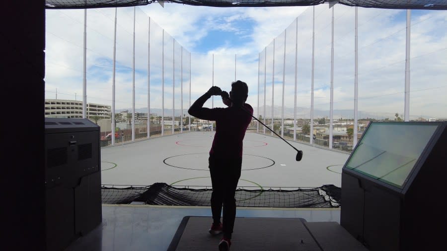 <em>Atomic Golf employee Ray Harsono tees off inside the facility. (KLAS)</em>