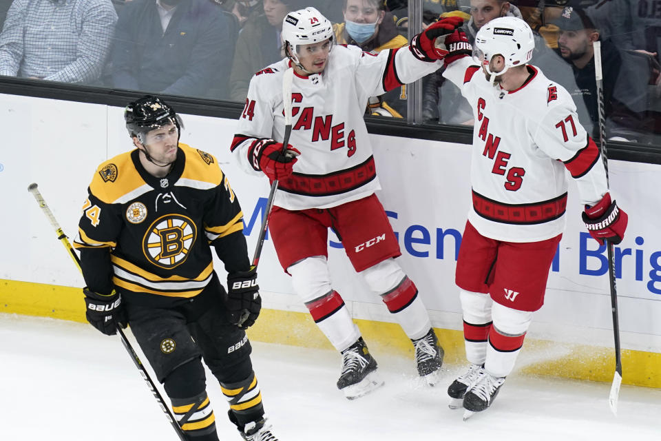 Carolina Hurricanes center Seth Jarvis, center, is congratulated by Tony DeAngelo (77) after his goal as Boston Bruins left wing Jake DeBrusk, left, skates past during the first period of an NHL hockey game, Tuesday, Jan. 18, 2022, in Boston. (AP Photo/Charles Krupa)