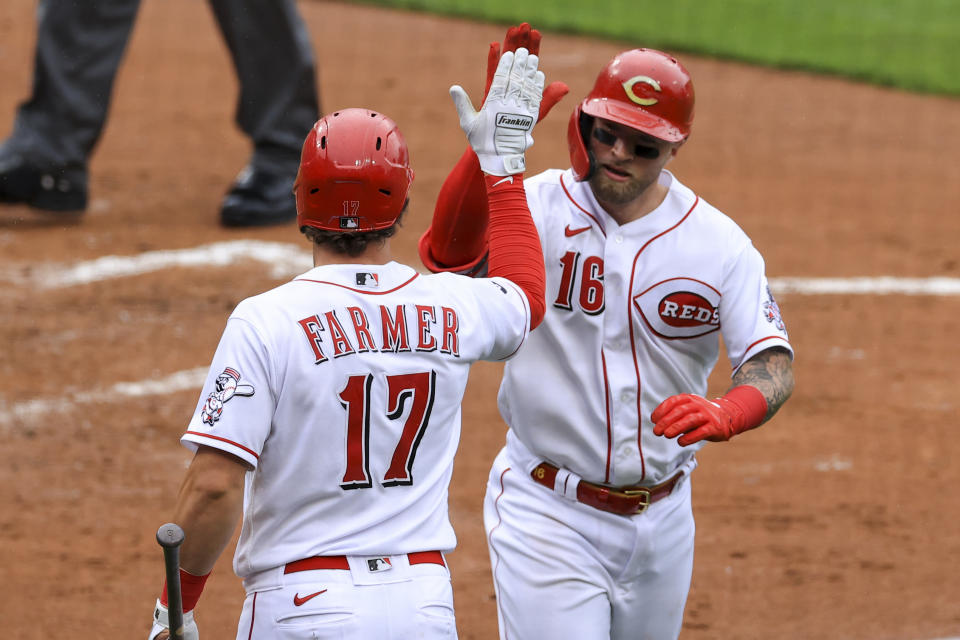 Cincinnati Reds' Kyle Farmer, left, celebrates a solo home run hit by Tucker Barnhart, right, during the second inning of a baseball game against the Cleveland Indians in Cincinnati, Saturday, April 17, 2021. (AP Photo/Aaron Doster)