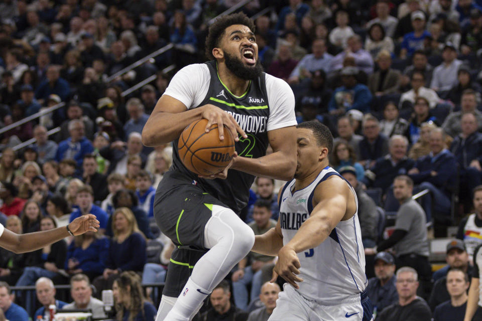 Minnesota Timberwolves center Karl-Anthony Towns, left, goes up for a shot while being defended by Dallas Mavericks forward Grant Williams, right, during the first half of an NBA basketball game, Wednesday, Jan. 31, 2024, in Minneapolis. (AP Photo/Bailey Hillesheim)