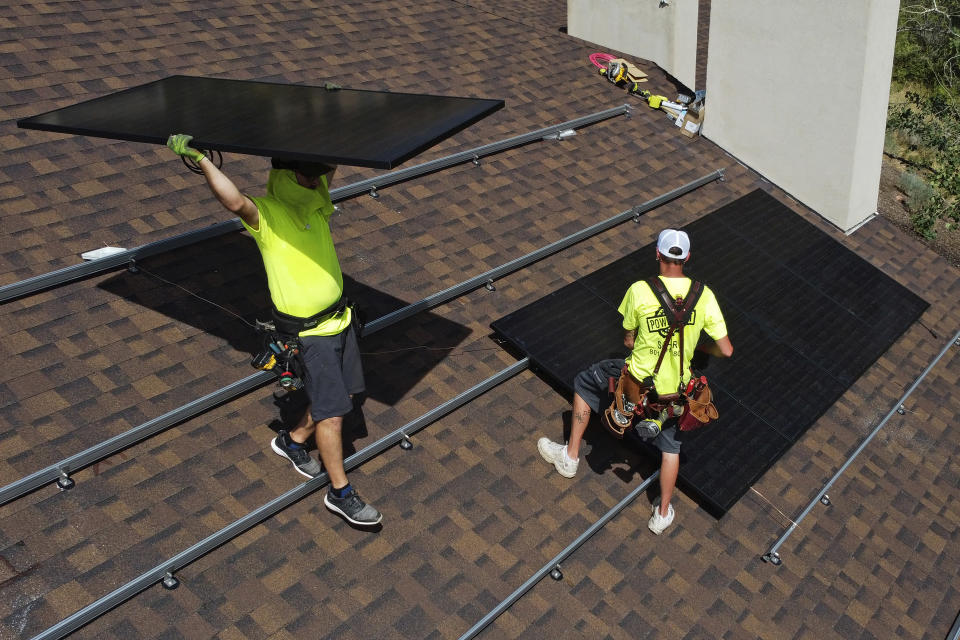 Workman with Power Shift Solar put solar panels on a house Wednesday, Aug. 10, 2022, in Salt Lake City. Congress is poised to pass a transformative climate change bill on Friday, Aug. 12. The crux of the long-delayed bill is to use incentives to accelerate the expansion of clean energy such as wind and solar power, speeding the transition away from the oil, coal and gas that largely cause climate change. (AP Photo/Rick Bowmer)