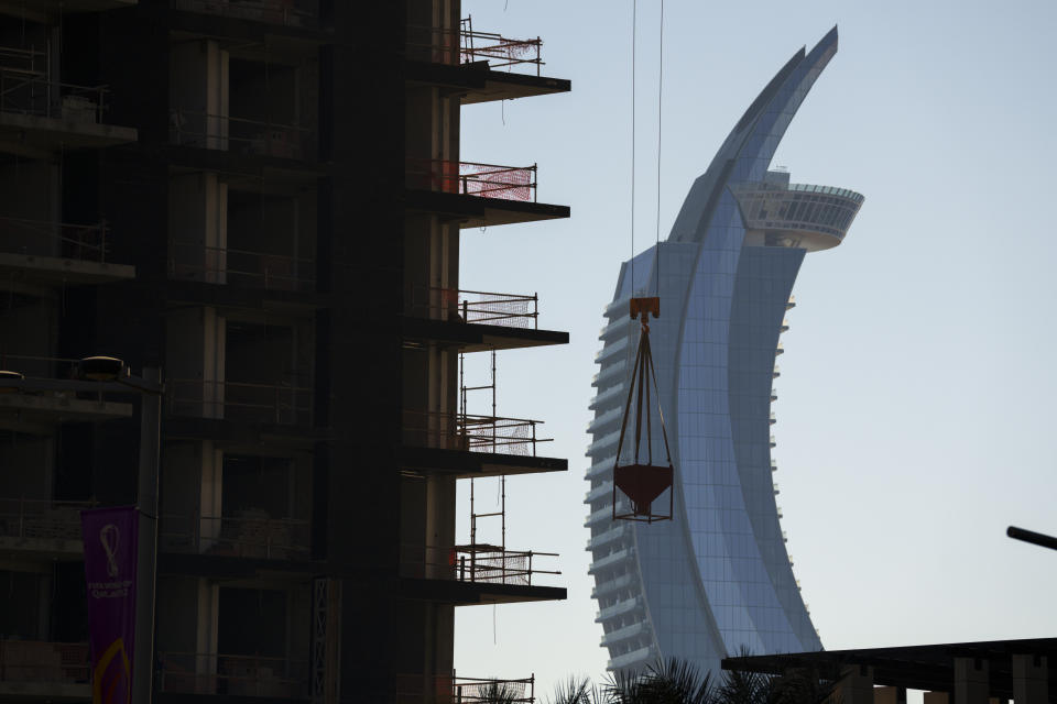 A crane operates on a construction cite with the Crescent Tower Lusail in the background in Doha downtown, Qatar, Thursday, Nov. 24, 2022. (AP Photo/Pavel Golovkin)