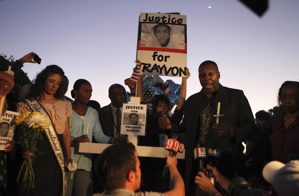 FILE - Marc Booker, right, leads a prayer during the candlelight vigil for Trayvon Martin at the Retreat at Twin Lakes in Sanford, Fla., March 25, 2012. The small city north of Orlando had a history of racial tensions even before Martin's killing. When local police didn't charge Zimmerman right away, thousands of protesters filled the streets. (AP Photo/Julie Fletcher, File)