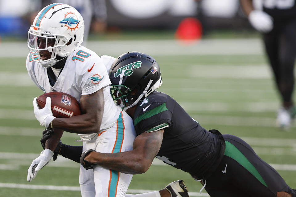 New York Jets cornerback D.J. Reed (4) tackles Miami Dolphins wide receiver Tyreek Hill (10) during the first quarter of an NFL football game, Friday, Nov. 24, 2023, in East Rutherford, N.J. (AP Photo/Noah K. Murray)