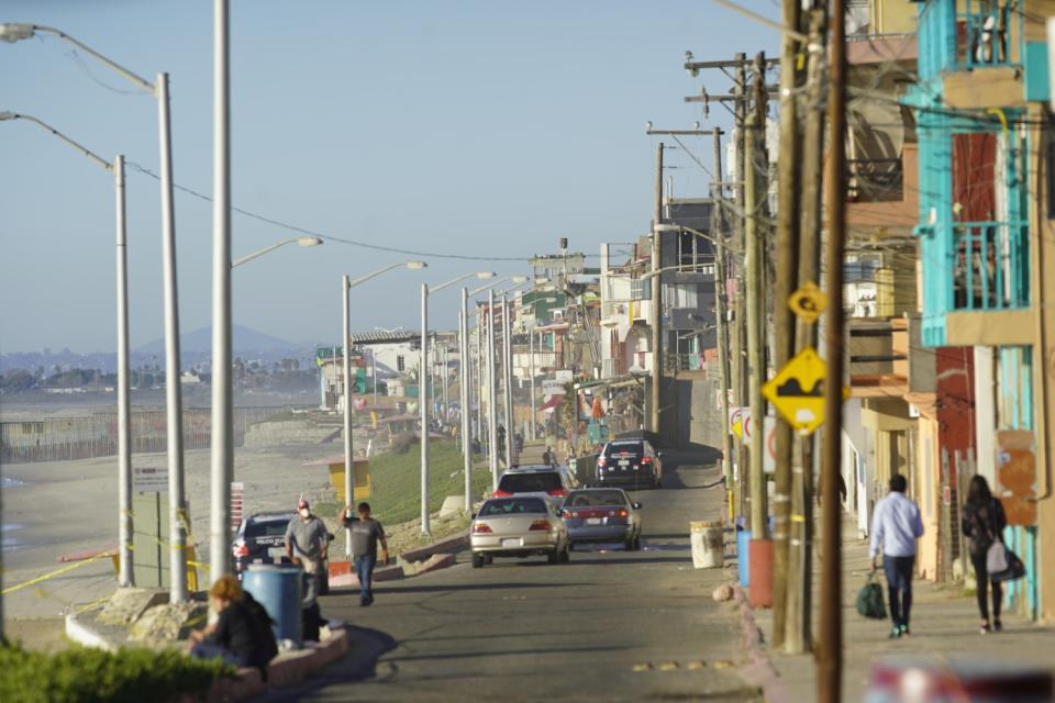 Pedestrians walk in a neighborhood alongside a beach.