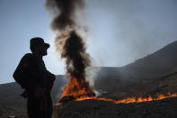 <p>An Afghan policeman watches as a cache of alcohol and drugs burns on the outskirts of Kabul on December 20, 2016.<br> Ninety eight tons of opium, heroin, hashish and alcoholic drinks were set on fire, officials said. (Photo: Shah Marai/ AFP/Getty Images) </p>