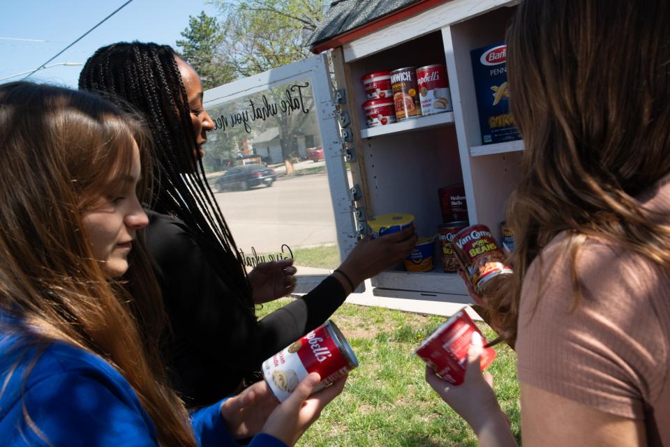 Washburn Rural students, from left, Naledi Mackenzie, Megan Weis and Sienna Hamilton fill up a blessing box on the corner of S.W. 32nd Street and Burlingame Road Monday afternoon. The trio are part of the Bee the Blessing group, which received grant funds to replenish more than 40 boxes around town.