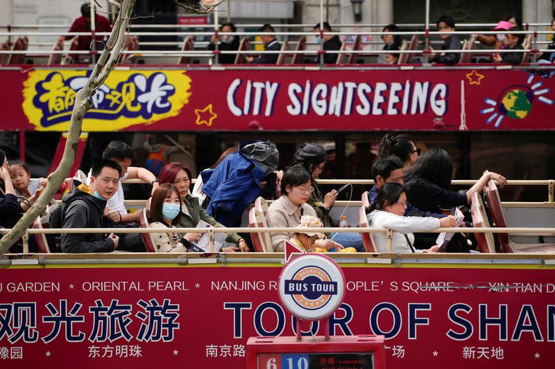 Tourists ride on a tourist double-decker bus in Shanghai