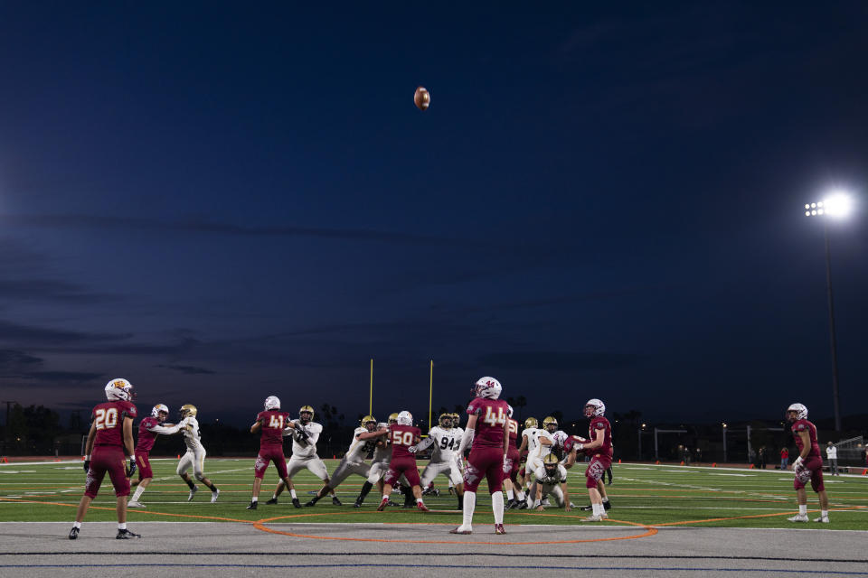 Dusk settles over the stadium as El Modena players attempt to defend a field goal by El Dorado in a high school football game in Orange, Calif., Friday, March 19, 2021. The team recently played its first football game in a year as more California counties ease coronavirus restrictions and life in the nation’s most populous state inches back to normalcy. (AP Photo/Jae C. Hong)