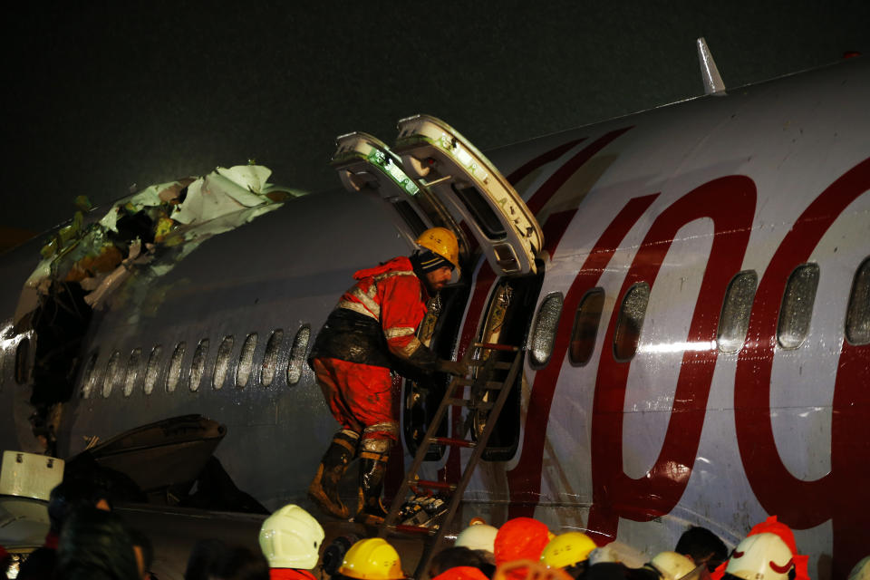 Rescue members and firefighters around the wreckage of a plane after it skidded off the runway at Istanbul's Sabiha Gokcen Airport, in Istanbul, Wednesday, Feb. 5, 2020. The plane skidded off the runway, crashing into a field and breaking into pieces. Authorities said at least 52 people were injured, and passengers were seen evacuating through the cracks in the plane. (AP Photo/Emrah Gurel)