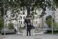 Jen Reid poses for photographs in front of the new black resin and steel statue portraying her, entitled "A Surge of Power (Jen Reid) 2020" by artist Marc Quinn after the statue was put up this morning on the empty plinth of the toppled statue of 17th century slave trader Edward Colston, which was pulled down during a Black Lives Matter protest in Bristol, England, Wednesday, July 15, 2020. On June 7 anti-racism demonstrators pulled the 18-foot (5.5 meter) bronze likeness of Colston down, dragged it to the nearby harbor and dumped it in the River Avon — sparking both delight and dismay in Britain and beyond. (AP Photo/Matt Dunham)