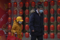 A man and a child wearing face masks to help protect from the coronavirus walk by a lantern decoration on display outside a mall in Beijing, Sunday, Jan. 23, 2022. Chinese authorities have called on the public to stay where they are during the Lunar New Year instead of traveling to their hometowns for the year's most important family holiday. (AP Photo/Andy Wong)