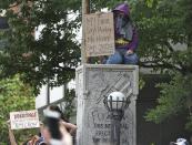 <p>A protester kneels atop the Confederate Memorial to protest in anticipation of a white supremacist march on Friday, Aug. 18, 2017 in Durham, N.C. The sheriff had issued a statement that he was investigating the rumors, but no gathering of white supremacists was apparent by midafternoon. However, officers blocked streets and businesses closed. (Photo: Chuck Liddy/The News & Observer via AP) </p>