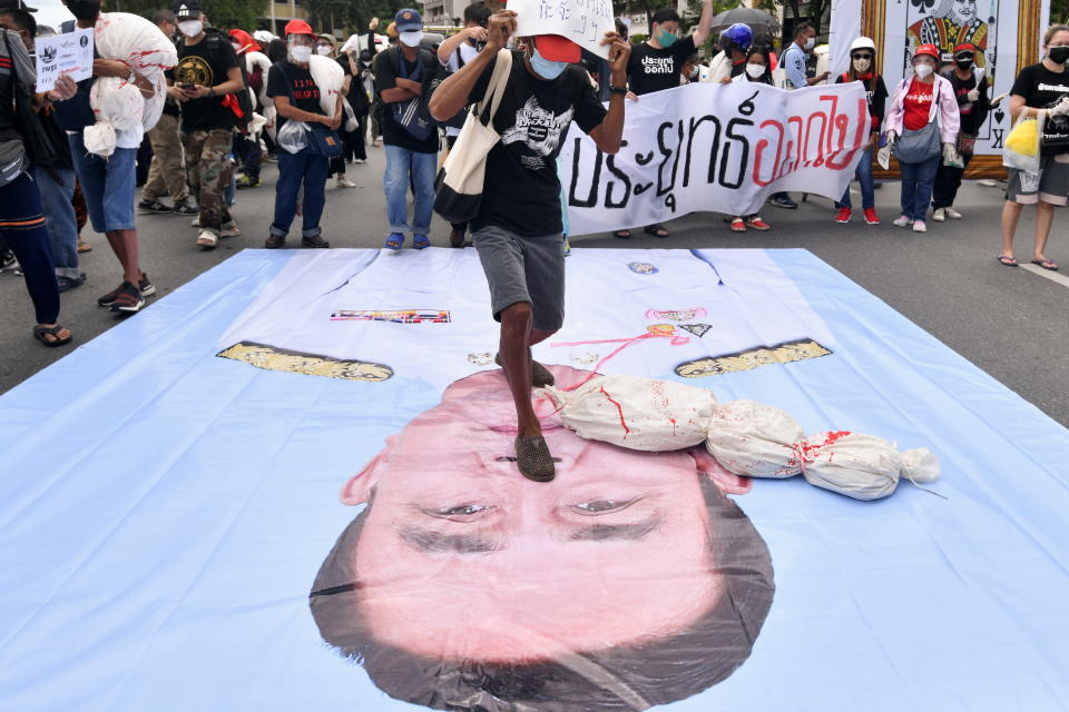 An anti-government protester steps on a picture of Thai Prime Minister Prayuth Chan-ocha, as they march toward the Government House, demanding Prayuth Chan-ocha resignation, mandatory vaccination policy and reform in the monarchy, in Bangkok, Thailand, July 18, 2021. REUTERS/Chalinee Thirasupa