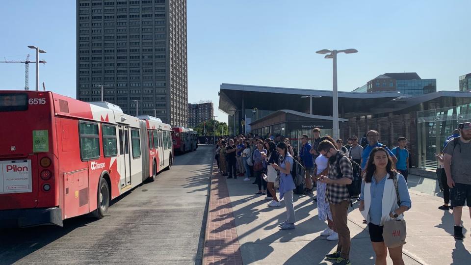 People wait for buses at Ottawa's Tunney's Pasture station July 19, 2023. It's the western end of the temporarily closed Confederation Line, meaning more buses are passing through.