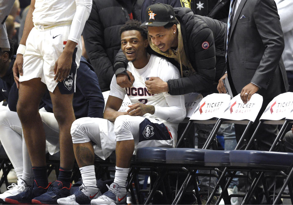 Connecticut's Alterique Gilbert sits and smiles as he is greeted by former teammate NBA G League Erie BayHawks' Jalen Adams before an NCAA college basketball game against Memphis, Sunday, Feb. 16, 2020, in Hartford, Conn. (AP Photo/Jessica Hill)