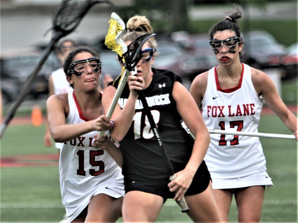 Mamaroneck's Dillon Troy (18) carries the ball, warding off a check by Fox Lane's Sophia Bueti during Mamaroneck's 10-8 Section 1 Class A girls lacrosse semifinal win at Fox Lane May 23, 2022.