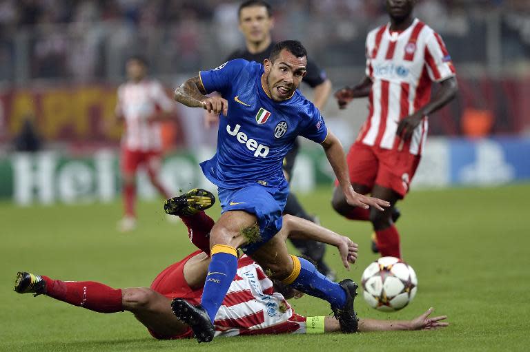 Juventus' Argentinian forward Carlos Tevez evades a tackle from Olympiacos' Greek defender Giannis Maniatis in their Group A Champions League clash in Athens on October 22, 2014