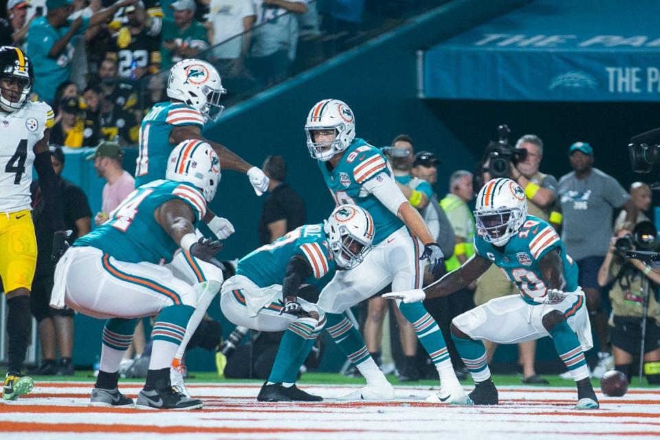 The Dolphins celebrate their first touchdown of Sunday night's game, a run by Raheem Mostert that capped their first drive.