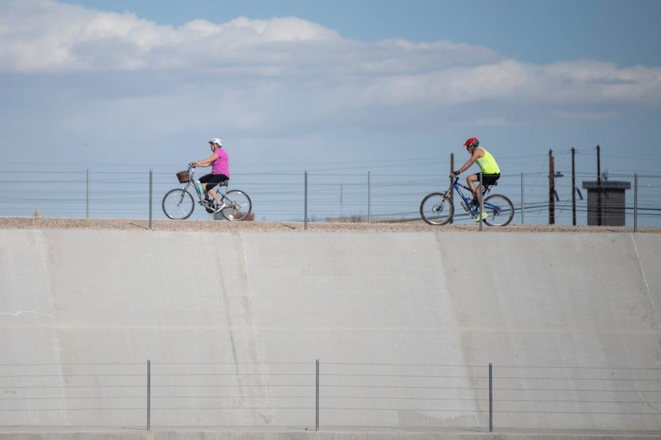 A pair of bicyclists ride along Pueblo's Arkansas River levee on Wednesday, March 6, 2024.