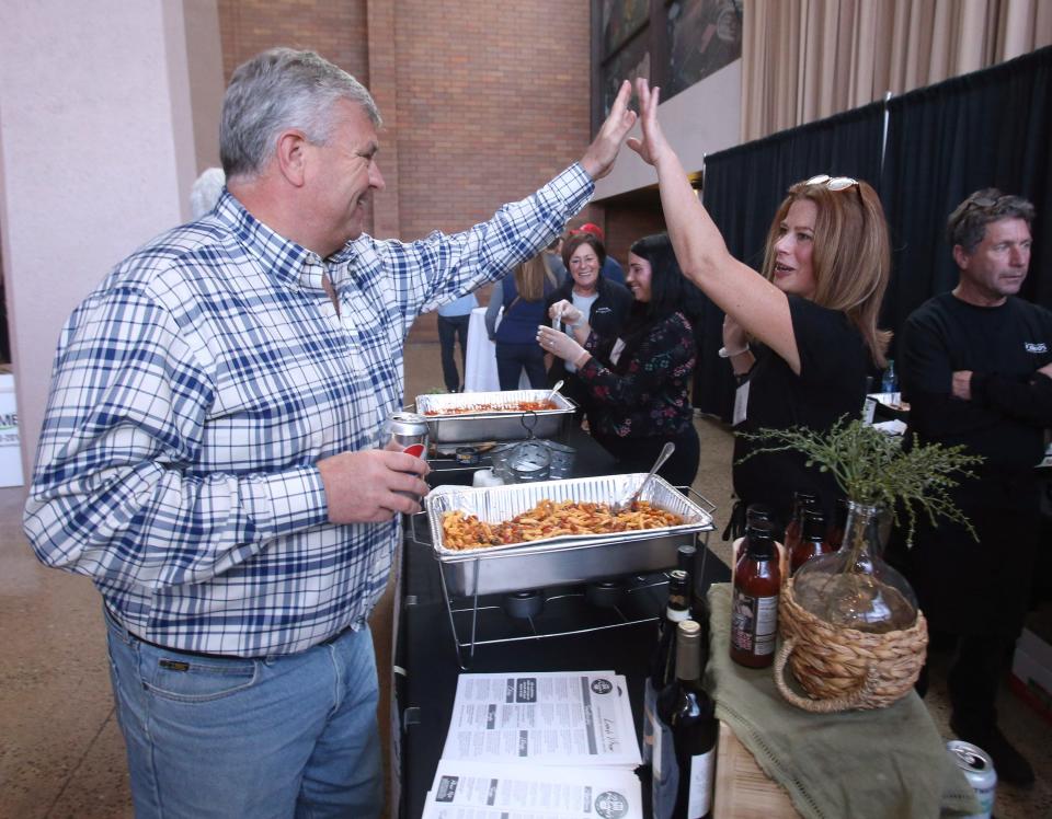 Doug Crawford high fives Melissa Wolfe at the Palombo's Italian Restaurant booth during Celebrity Cuisine at the Canton Memorial Civic Center on Tuesday. The event raised funds for the Akron-Canton Regional Foodbank's food rescue and hunger relief program.