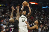 Milwaukee Bucks forward Khris Middleton (22) looks to pass under pressure from Miami Heat guard Kyle Lowry (7) and forward P.J. Tucker (17) during the second half of an NBA basketball game, Wednesday, Dec. 8, 2021, in Miami. The Heat defeated the Bucks 113-104. (AP Photo/Marta Lavandier)